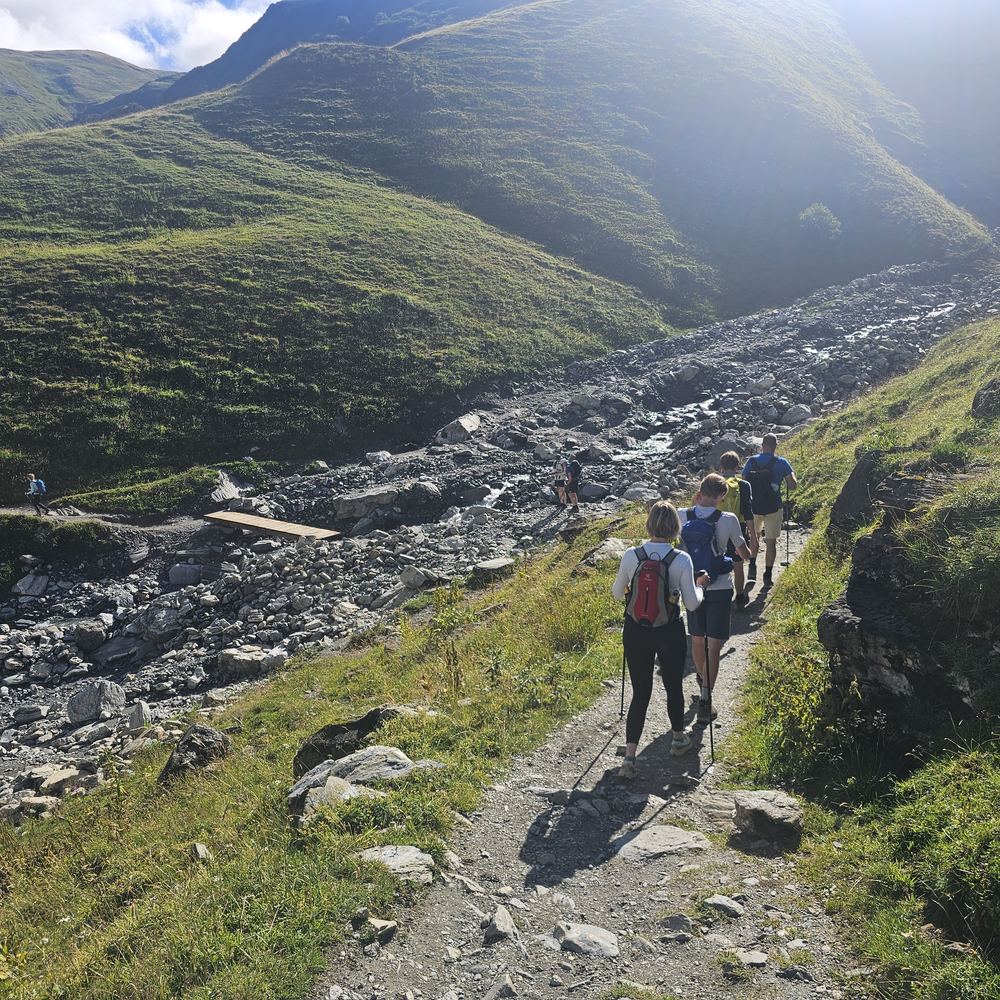 Wandelgroep daalt af tijdens de Mont Blanc Trail, met wandelstokken op technisch terrein